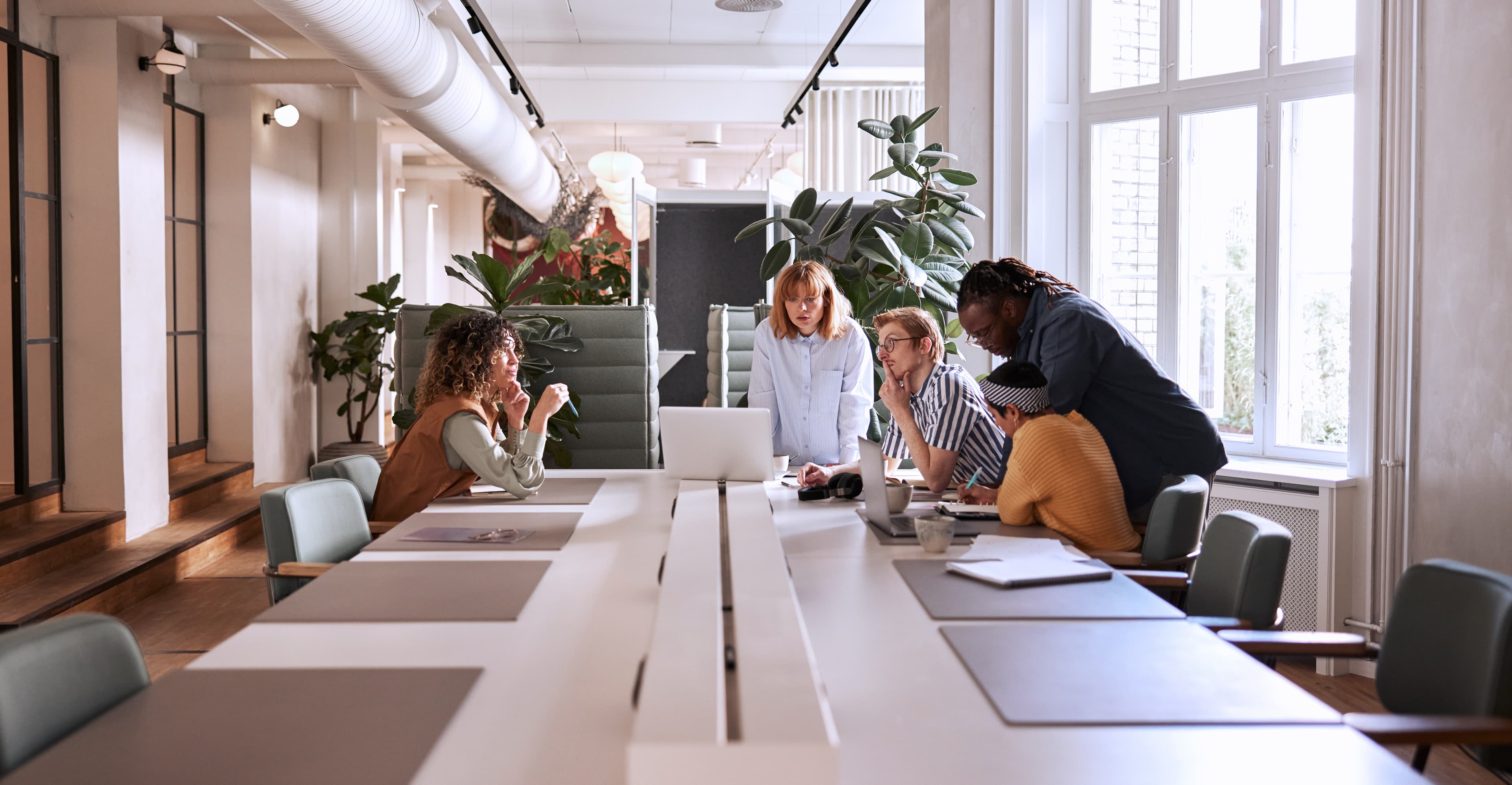 Diverse group of young businesspeople discussing a project during a meeting together around a table in a modern office